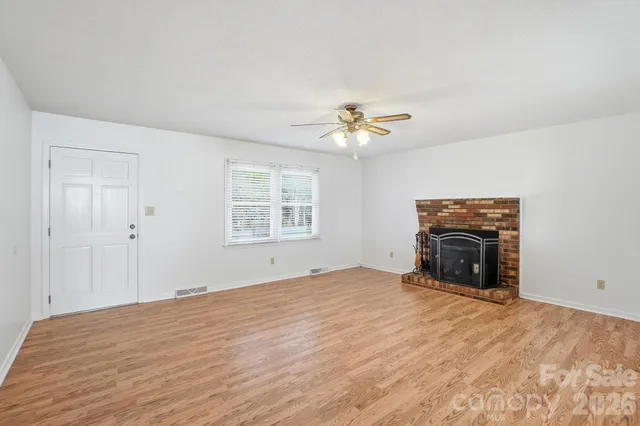 a view of empty room with a fireplace and chandelier fan