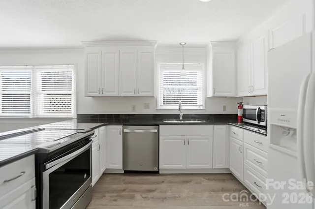 a kitchen with granite countertop white cabinets sink and stainless steel appliances