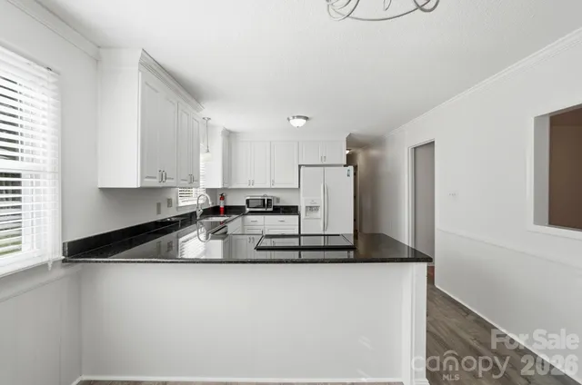 a kitchen with kitchen island a sink a refrigerator and white cabinets