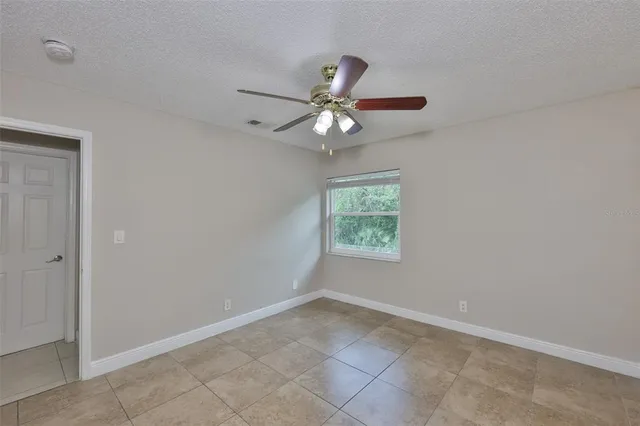 an empty room with a window and a fan