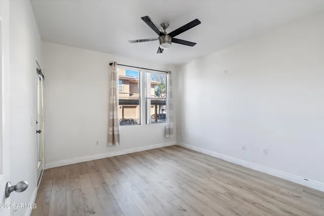 an empty room with wooden floor a ceiling fan and windows