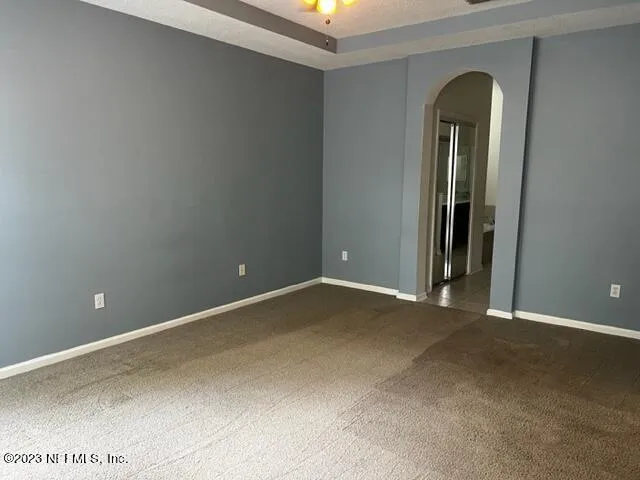a view of an empty room with window and chandelier fan