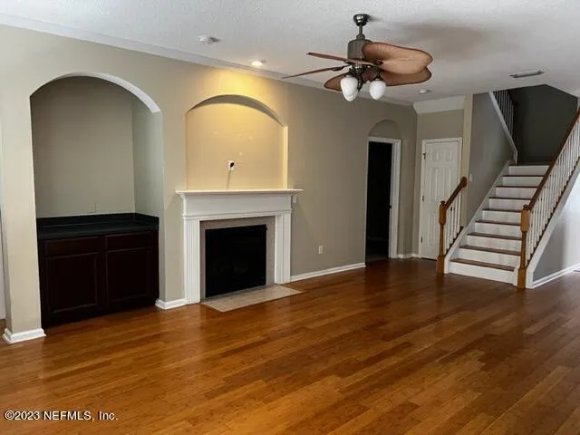 a view of an empty room with wooden floor a fireplace and a window