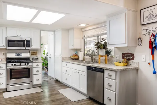 a kitchen with stainless steel appliances a stove a sink cabinets and a window