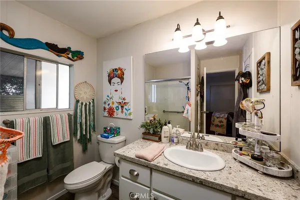a bathroom with a granite countertop sink mirror vanity and toilet