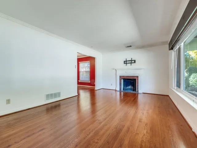 an empty room with wooden floor fireplace and windows