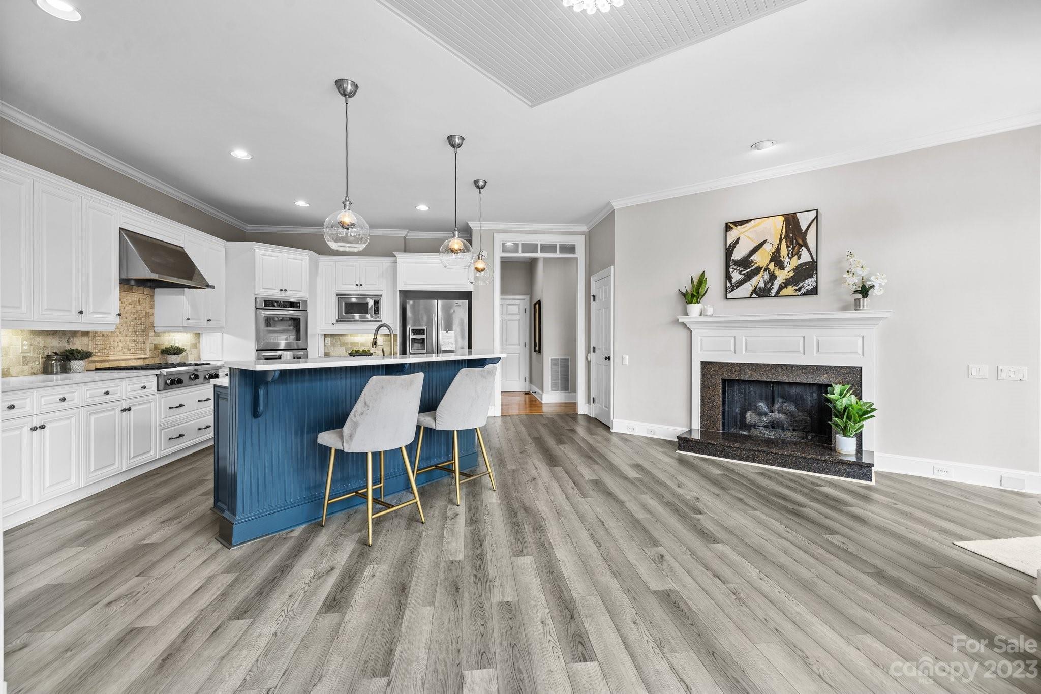 4732 Old Course Drive Charlotte, NC 28277 - Photo 18 of 48 a open kitchen with stainless steel appliances granite countertop a stove a refrigerator a fireplace with a dining table and chairs with wooden floor