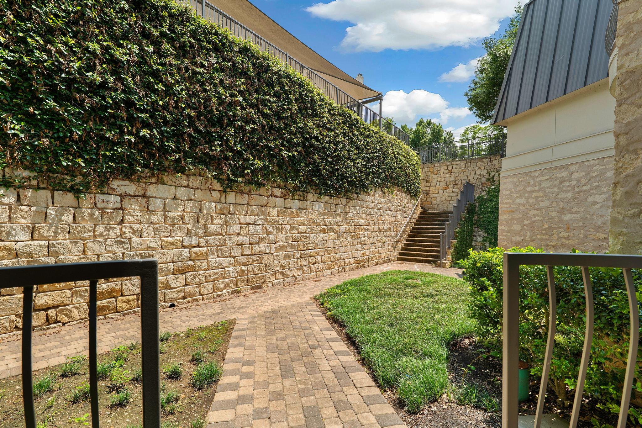 2918 Ranch Road 620, Unit J162 Austin, TX 78734 - Photo 4 of 26 Looking out from front porch entry with stone retaining wall with integrated landscaping, paver pathway, and exterior stairs