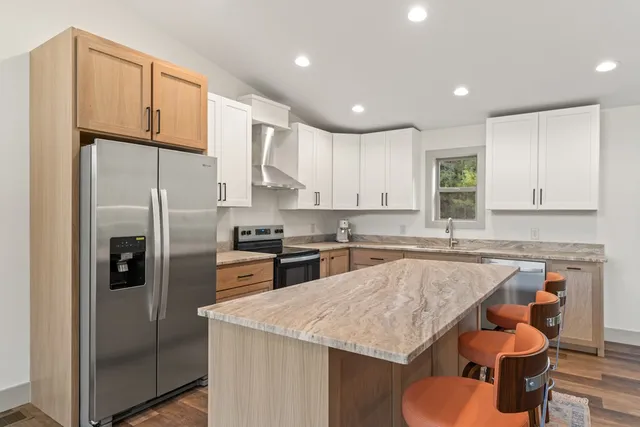 a kitchen with kitchen island granite countertop a sink a stove and cabinets