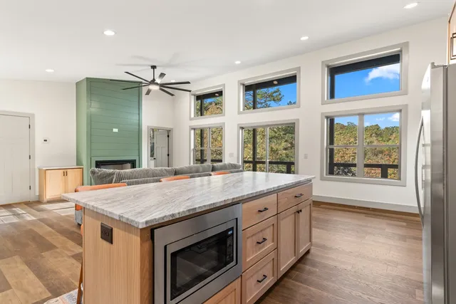 a kitchen with stainless steel appliances granite countertop a stove top oven a sink dishwasher and a refrigerator with wooden floor