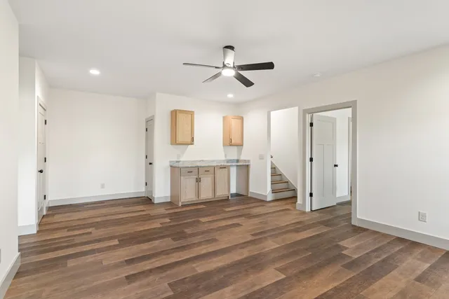 a view of an empty room with window and wooden floor