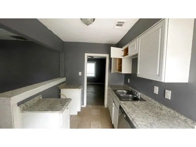 a kitchen with a sink a stove top oven and cabinetry