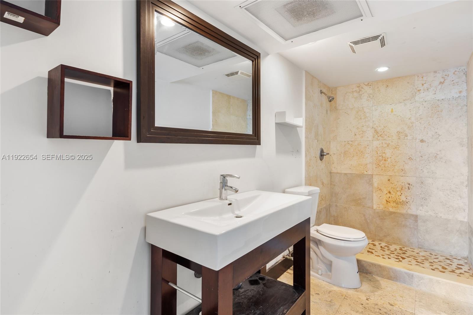 11111 Biscayne Boulevard, Unit 10H Miami, FL 33181 - Photo 11 of 22 a bathroom with a toilet a sink a light fixture and mirror
