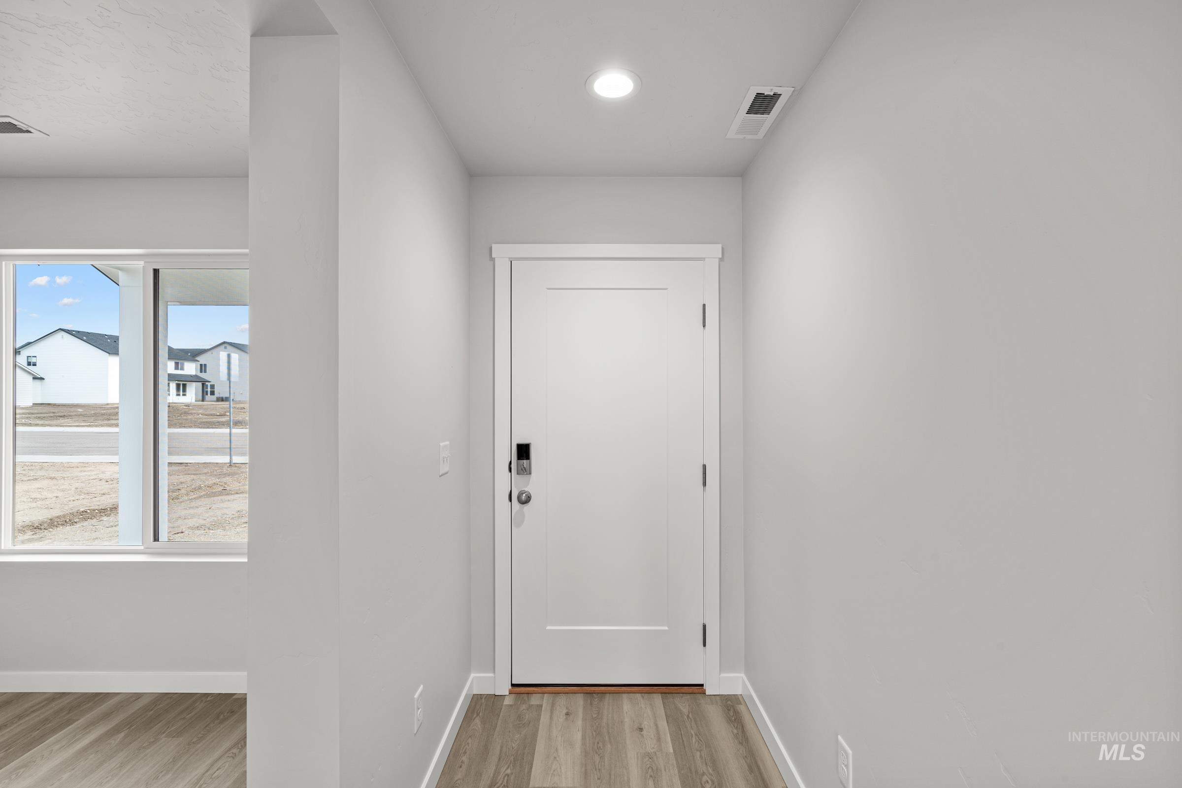 14056 Shiny Spruce Street Caldwell, ID 83607 - Photo 2 of 25 Entryway featuring wood-finish flooring, a white paneled door with a smart lock, and recessed ceiling lighting