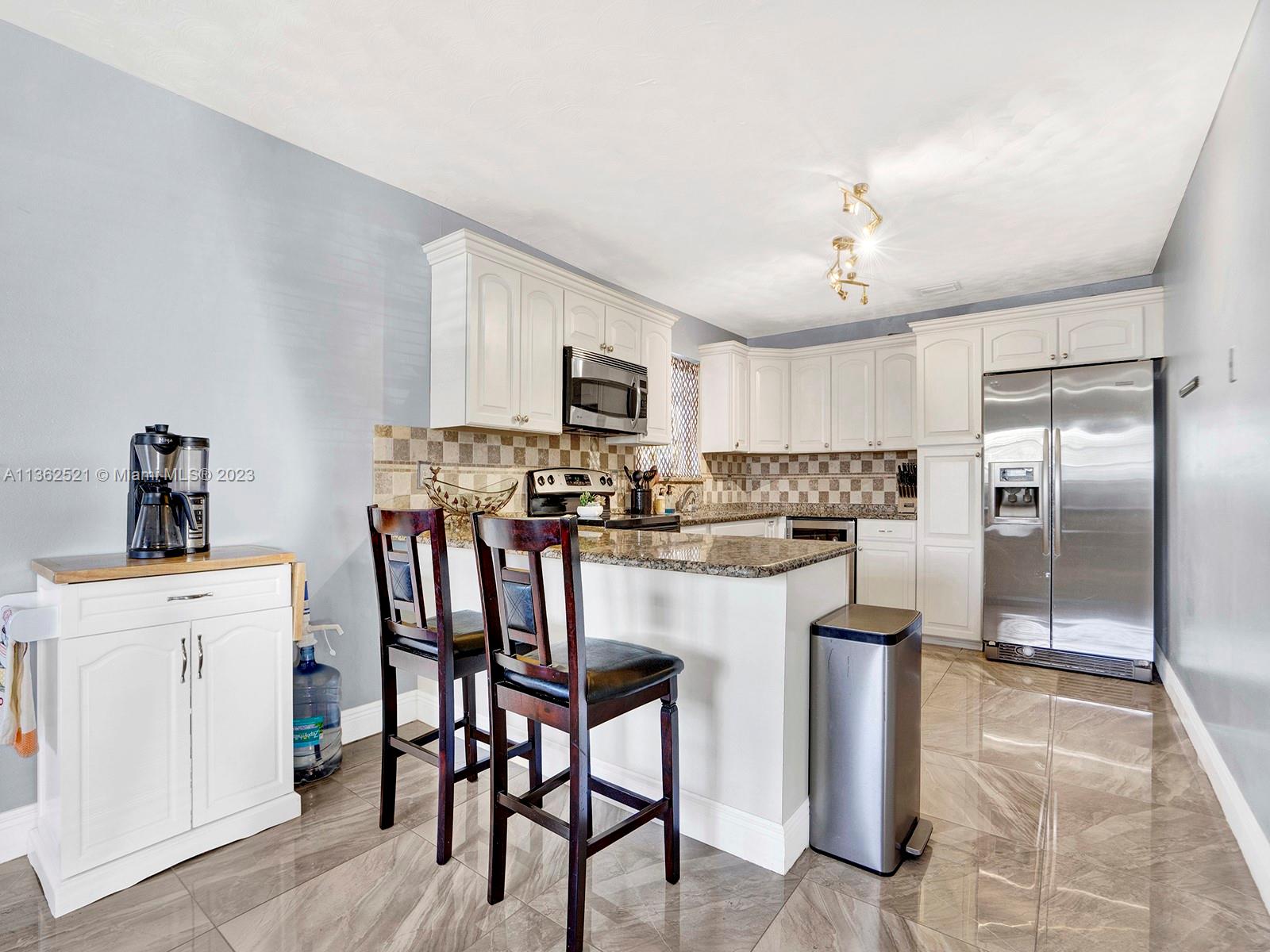 131 Northeast 17th Street Homestead, FL 33030 - Photo 6 of 24 a kitchen with stainless steel appliances granite countertop a stove a refrigerator a sink a dining table and chairs