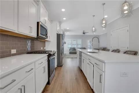 a kitchen with kitchen island granite countertop a sink a stove oven a counter space and cabinets