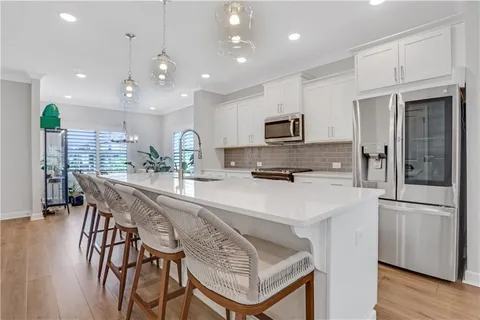 a kitchen with stainless steel appliances kitchen island granite countertop a refrigerator a stove a sink a dining table and chairs