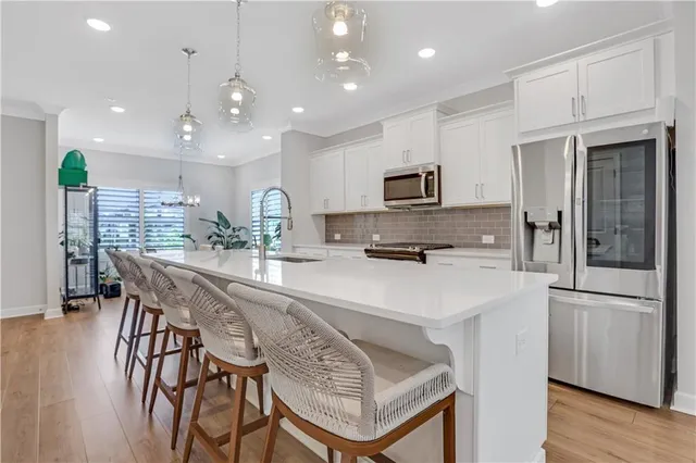 a kitchen with stainless steel appliances kitchen island granite countertop a refrigerator a stove a sink a dining table and chairs