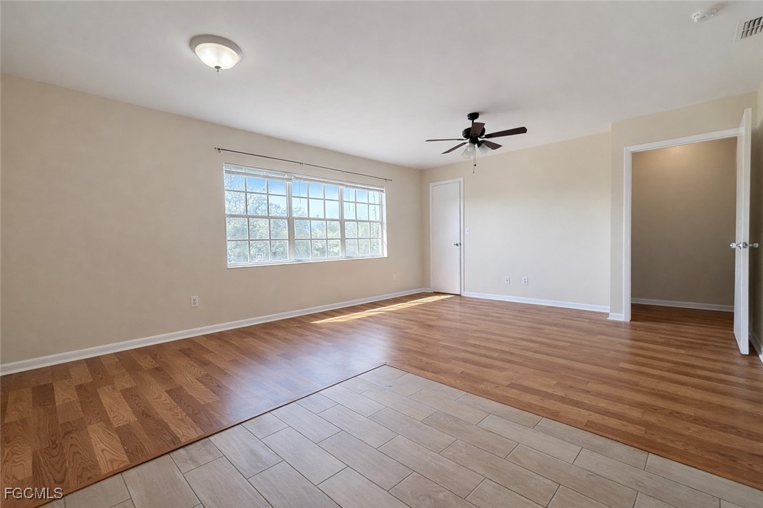 5014 26th Street Southwest Lehigh Acres, FL 33973 - Photo 6 of 20 an empty room with wooden floor ceiling fan and windows