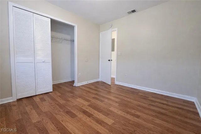 a view of an empty room with wooden floor and closet