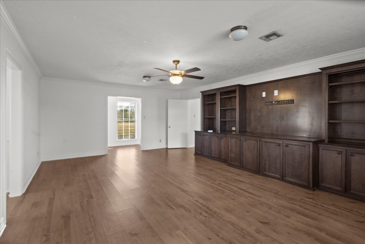 105 Alice Street Anahuac, TX 77514 - Photo 23 of 39 a view of an empty room with wooden floor and a kitchen