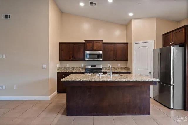 a kitchen with stainless steel appliances granite countertop a sink a stove a refrigerator and a microwave