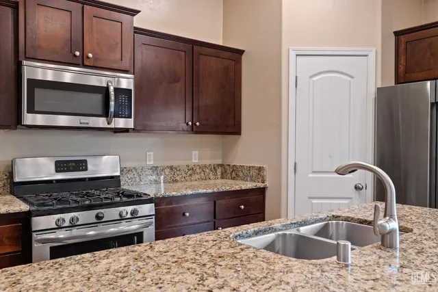a kitchen with stainless steel appliances granite countertop a stove microwave and sink