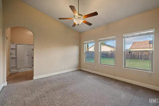 an empty room with windows and fan