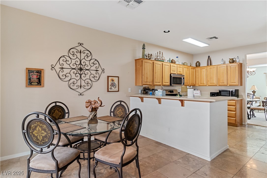 2078 Willow Bay Road Laughlin, NV 89029 - Photo 25 of 99 Dining space featuring a kitchen bar, a peninsula, light brown cabinetry, light countertops, and appliances with stainless steel finishes