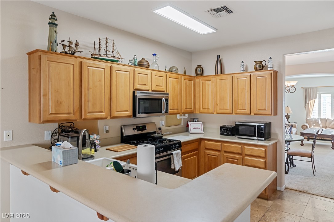 2078 Willow Bay Road Laughlin, NV 89029 - Photo 26 of 99 Kitchen with light countertops, appliances with stainless steel finishes, a peninsula, a breakfast bar area, and light brown cabinets