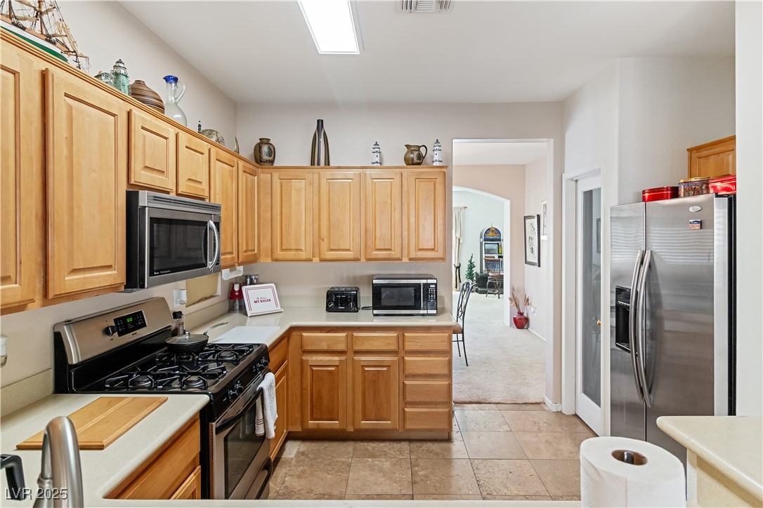 2078 Willow Bay Road Laughlin, NV 89029 - Photo 27 of 99 Kitchen with stainless steel appliances, light countertops, arched walkways, light colored carpet, and light brown cabinets