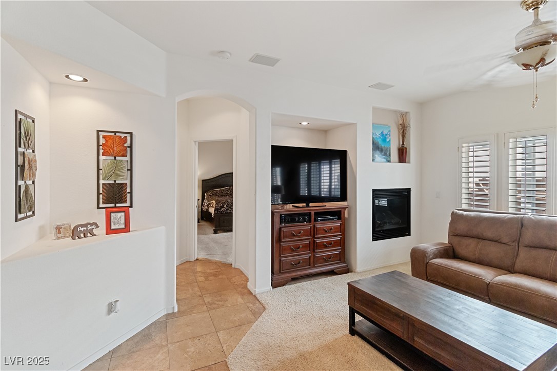 2078 Willow Bay Road Laughlin, NV 89029 - Photo 30 of 99 Family Room with light colored carpet, arched walkways, a glass covered fireplace, light tile patterned floors, and recessed lighting