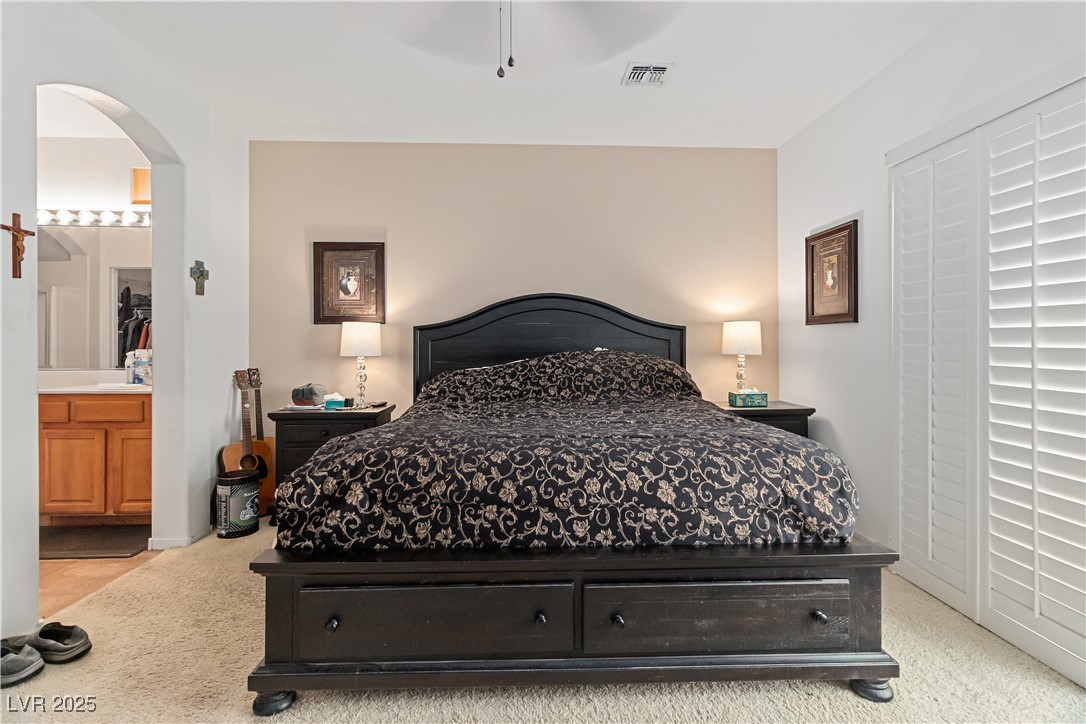 2078 Willow Bay Road Laughlin, NV 89029 - Photo 33 of 99 Primary Bedroom with light colored carpet, connected bathroom, arched walkways, and a ceiling fan