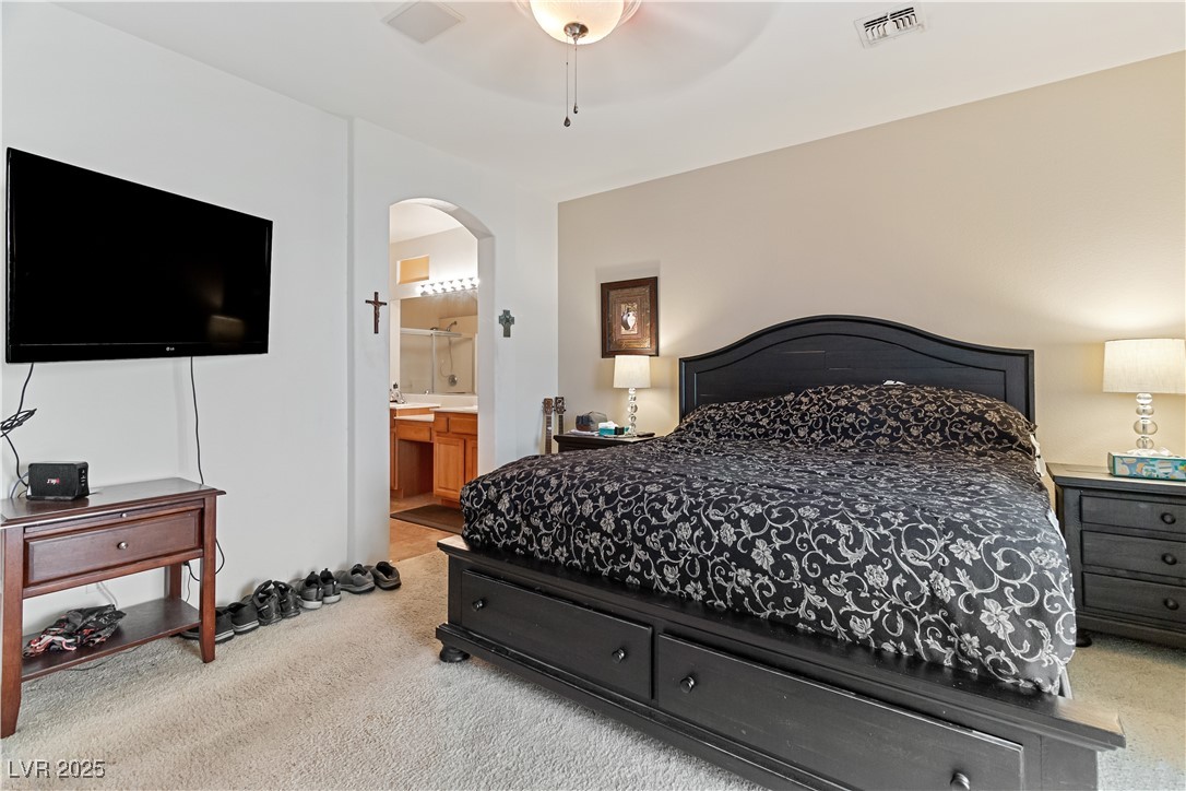 2078 Willow Bay Road Laughlin, NV 89029 - Photo 34 of 99 Primary Bedroom with light carpet, ensuite bathroom, arched walkways, and a ceiling fan