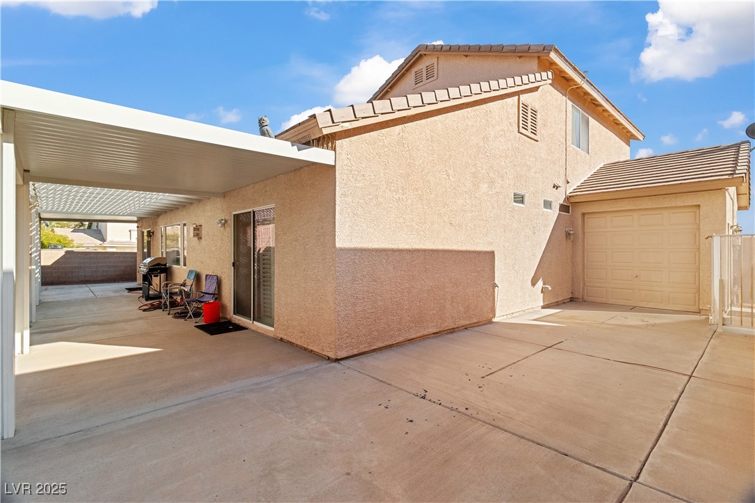 2078 Willow Bay Road Laughlin, NV 89029 - Photo 67 of 99 View of side of home with stucco siding, a patio, a tiled roof, and the 3 car garage pull-through bay to backyard