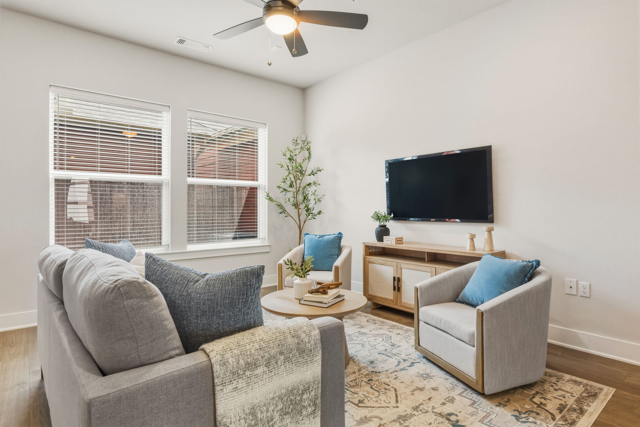 2929 Moreno Street Austin, TX 78723 - Photo 17 of 40 Living area featuring wood-finish flooring, two large windows with blinds, a ceiling fan with integrated lighting, and a neutral color palette