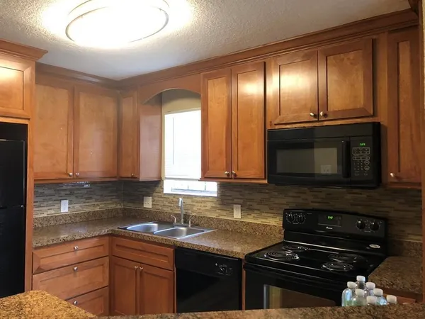 a kitchen with granite countertop cabinets stove top oven and sink