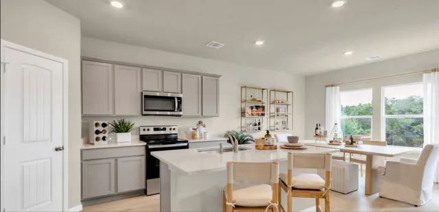 a kitchen with a sink a stove a refrigerator and white cabinets with wooden floor