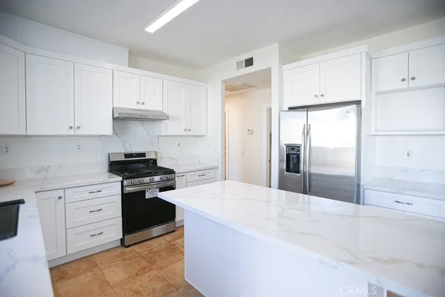 a kitchen with stainless steel appliances granite countertop white cabinets and a stove
