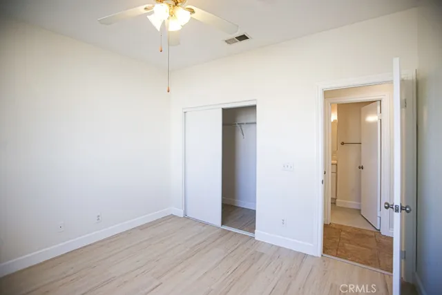 an empty room with wooden floor and a ceiling fan
