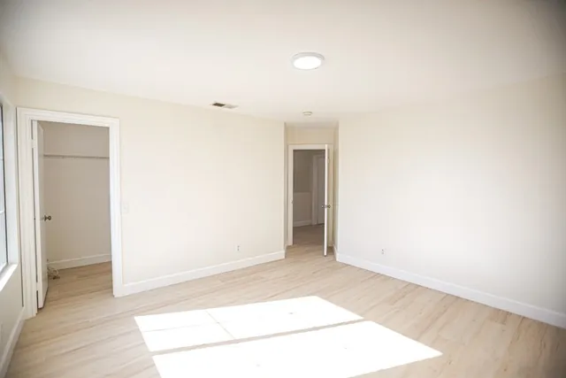 a view of an empty room with a window and wooden floor
