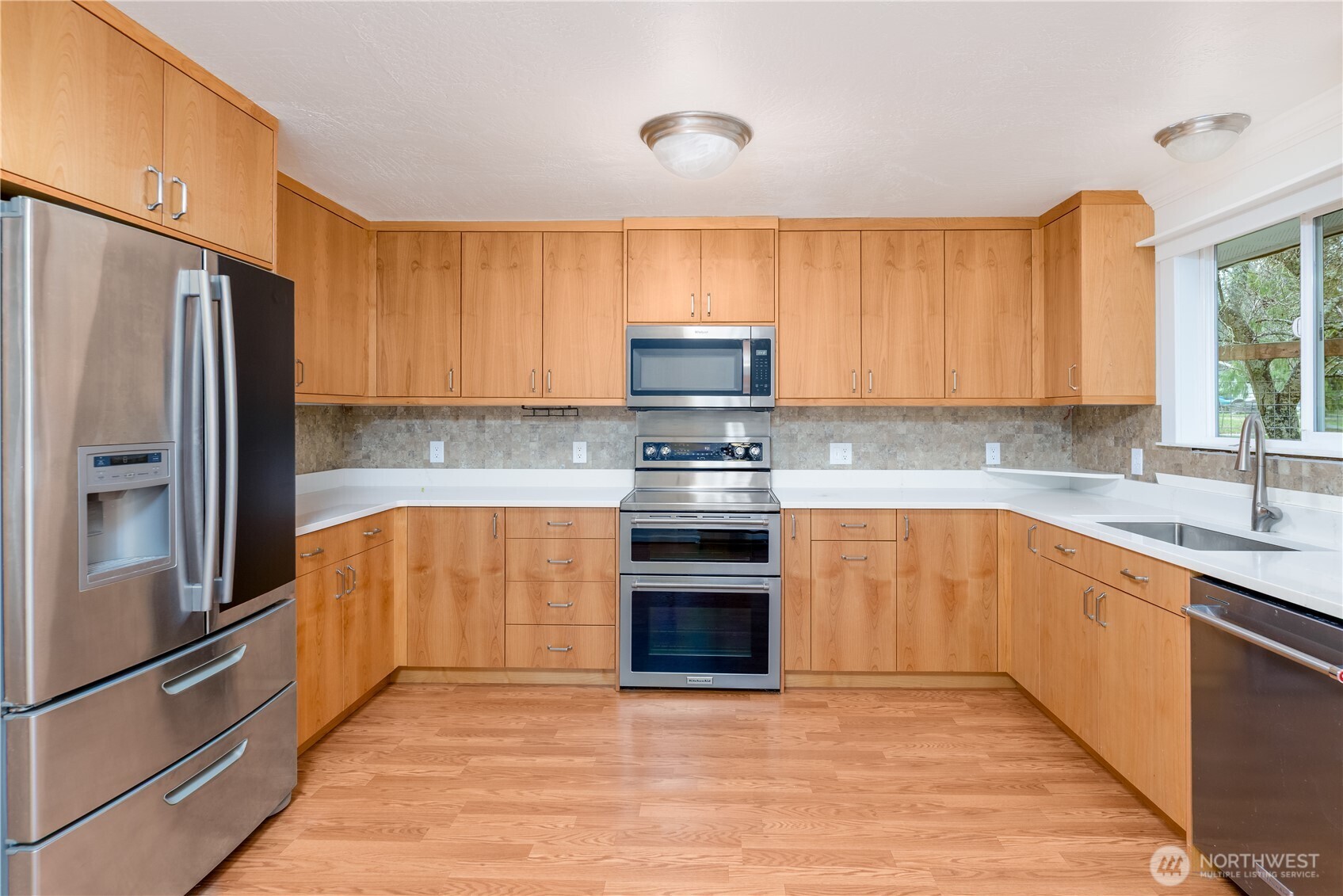 4109 South Reddick Road Port Angeles, WA 98363 - Photo 9 of 38 a kitchen with stainless steel appliances granite countertop a stove top oven a sink and a refrigerator with wooden floors