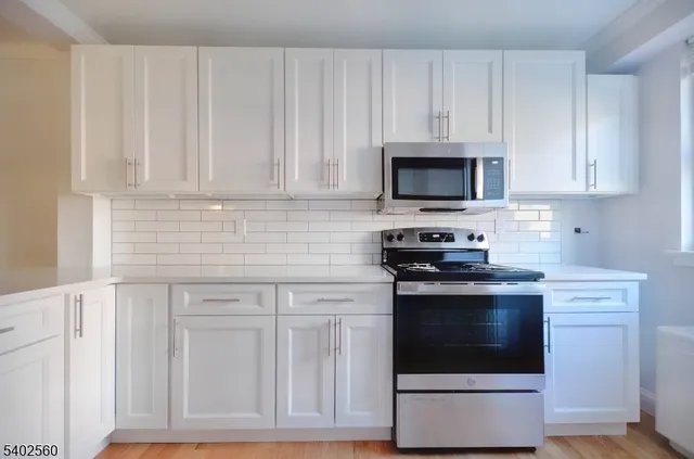 a kitchen with granite countertop white cabinets and stainless steel appliances