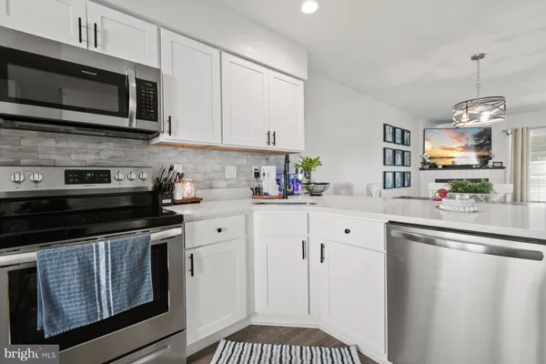 a kitchen with stainless steel appliances granite countertop white cabinets a stove a sink and dishwasher