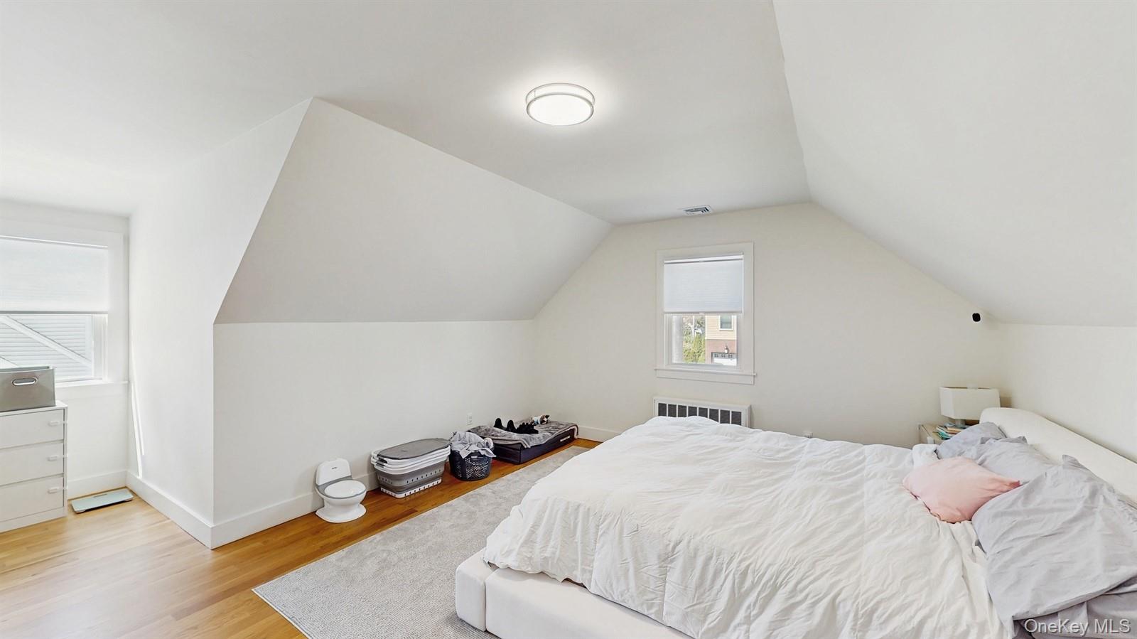170 Wetherill Road Garden City, NY 11530 - Photo 19 of 23 Bedroom featuring visible vents, baseboards, light wood finished floors, radiator, and lofted ceiling
