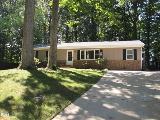 a view of a yard in front of a house with large tree