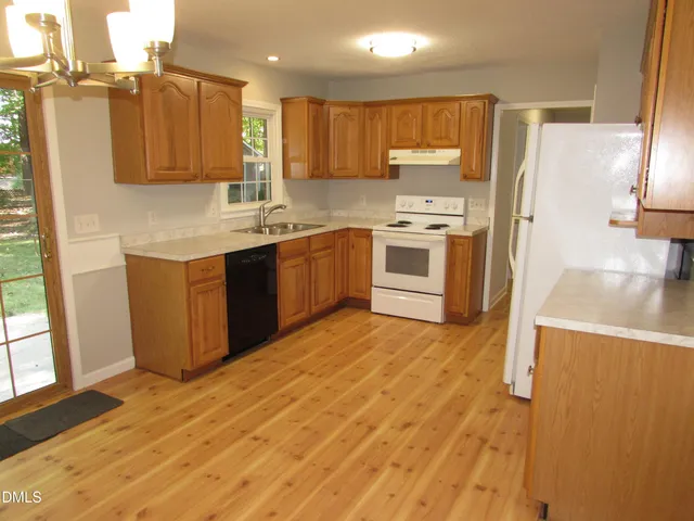 a kitchen with stainless steel appliances granite countertop a stove a sink and a refrigerator with wooden floor