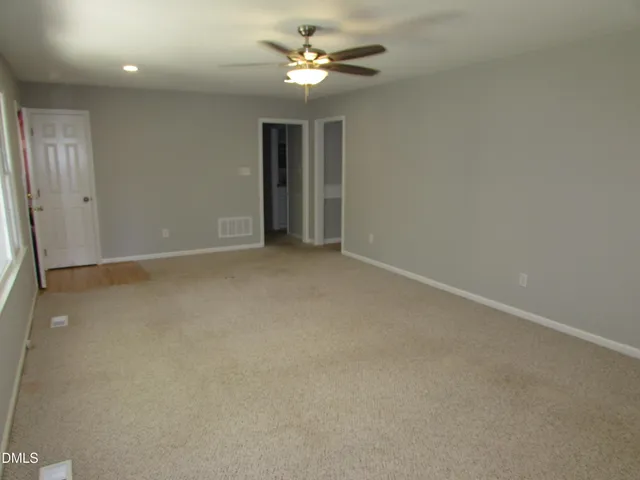 an empty room with a ceiling fan and a window