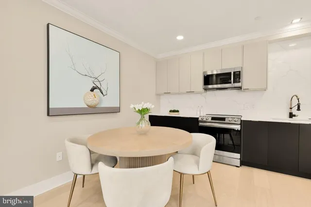 a kitchen with stainless steel appliances a stove a sink a microwave a dining table and chairs
