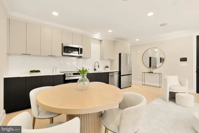 a open kitchen with stainless steel appliances kitchen island granite countertop a refrigerator a sink a stove a dining table and chairs with wooden floor